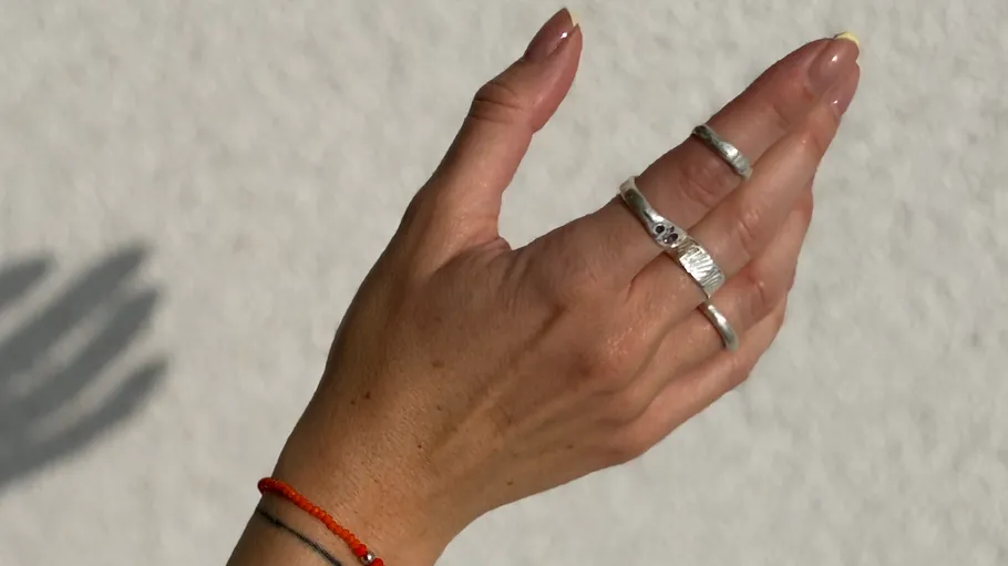 Hand mit Ringen und Schatten, weißer Hintergrund.