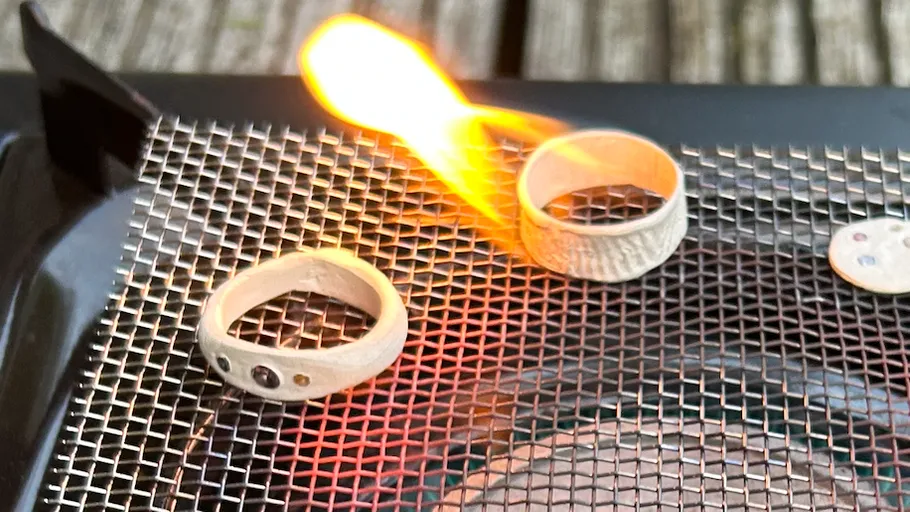 Two rings on mesh with flame nearby.