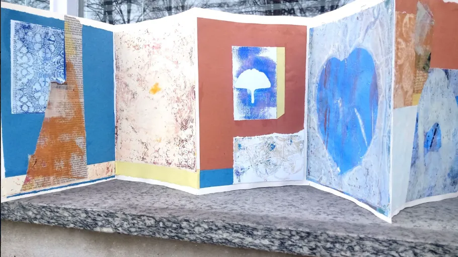 Folded art book with abstract paintings, outdoors.