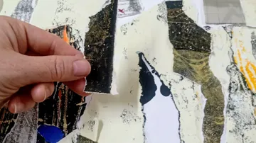 Hand zerreißt Papier in einer Kunstcollage.