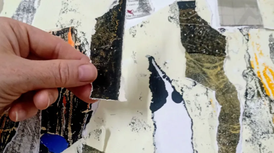 Hand zerreißt Papier in einer Kunstcollage.