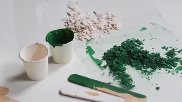 Zerkleinertes grünes Material mit Bechern und Stäbchen.