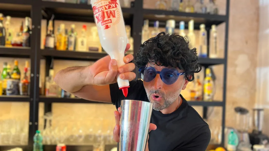 Mann gießt Flüssigkeit in Shaker an Bar.