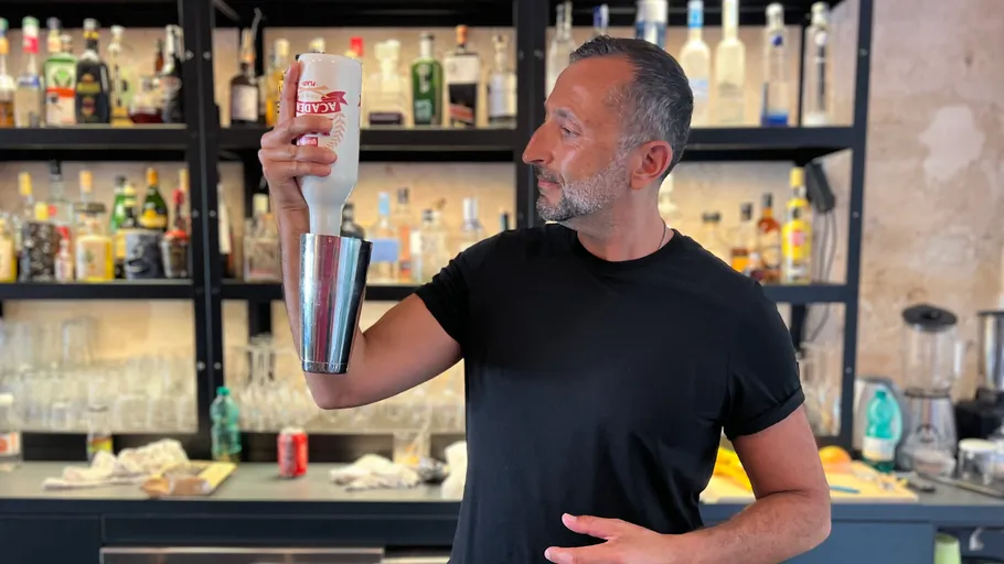Mann hält Flasche kopfüber in der Bar.