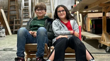 Two children sitting in a workshop setting.