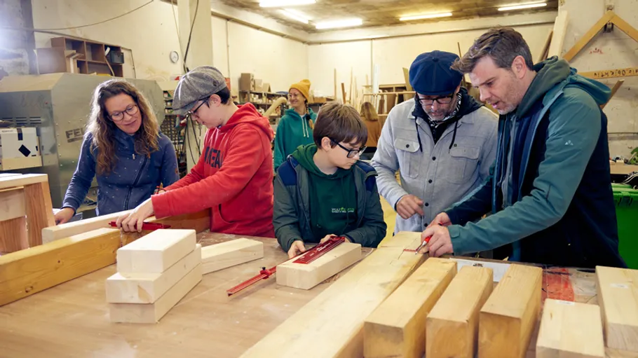 Menschen arbeiten in einer Werkstatt mit Holzwerkzeugen.