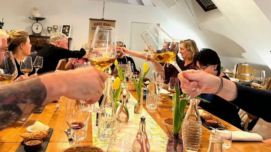 People clinking wine glasses at a dining table.