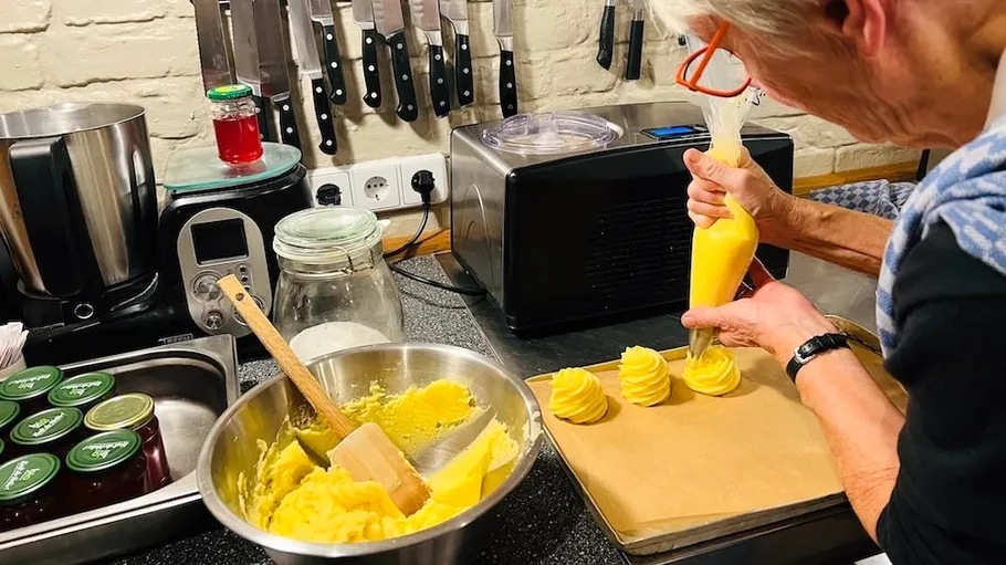 Person piping dough in a kitchen.