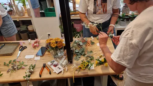 People arranging flowers on a wooden table.