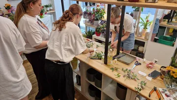 Drei Personen arrangieren Blumen im Laden.