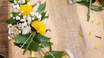 Yellow and white flowers arranged on wooden table.