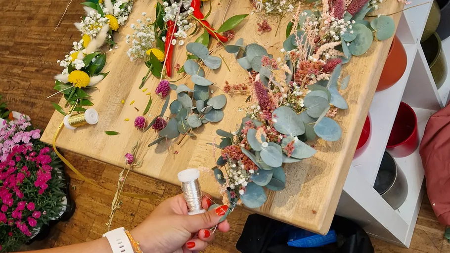Hand crafting floral wreaths on a wooden table.
