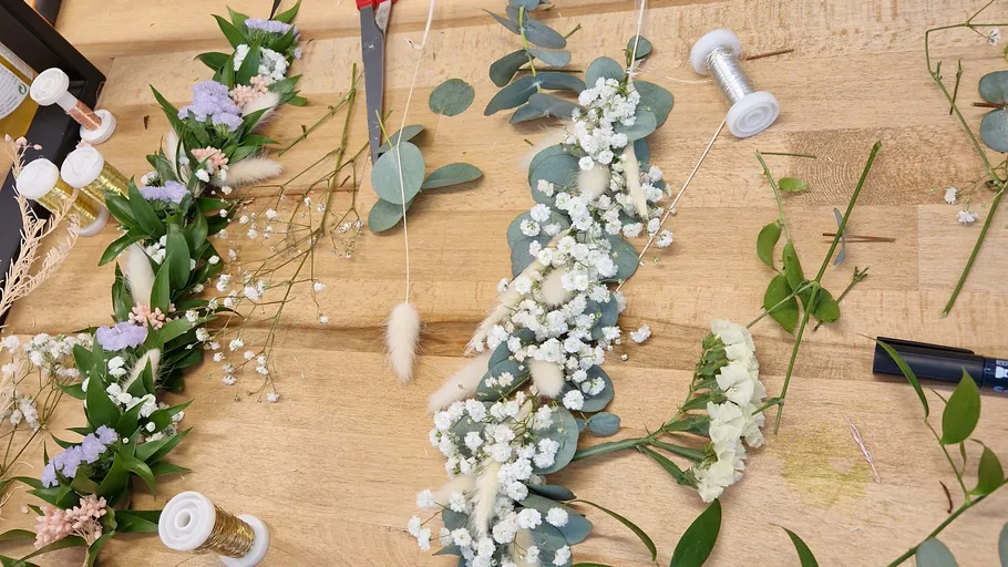 Floral arrangement in progress on wooden table.