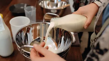 Person pouring milk into a mixing bowl.