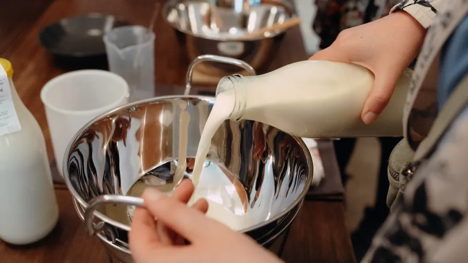 Person pouring milk into a mixing bowl.