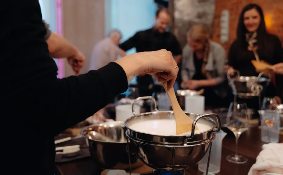 Person rührt Käsefondue bei einer Versammlung.