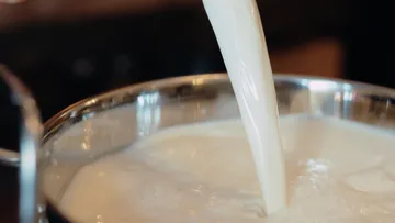 Milk pouring into a metal pot.