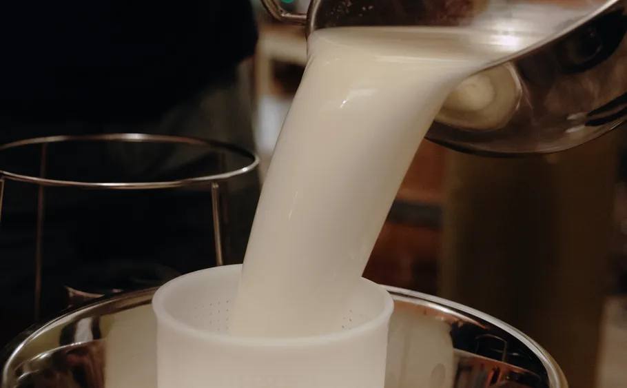 Milk being poured through a strainer.