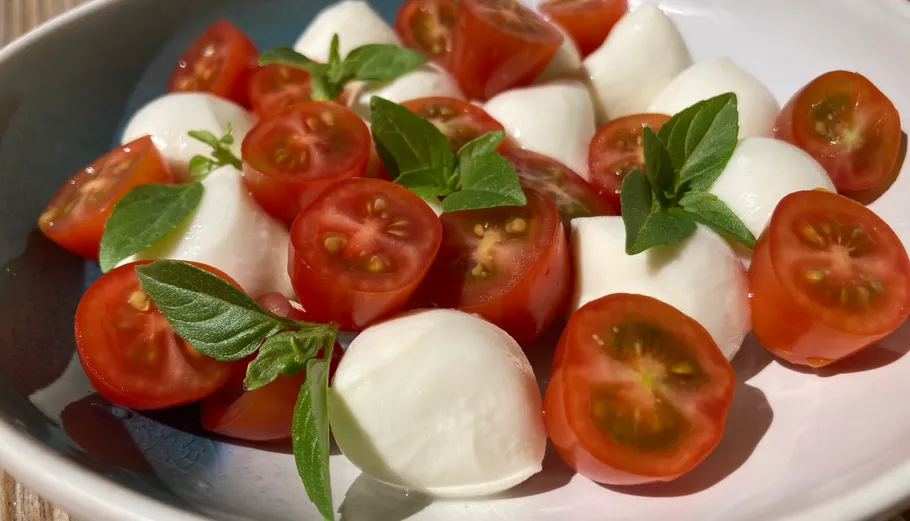 Tomaten-Mozzarella-Salat mit Basilikumblättern.