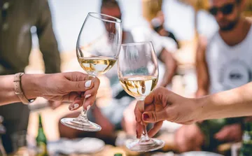 Two people clinking wine glasses outdoors.