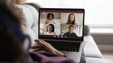 Person video conferencing on laptop at home.