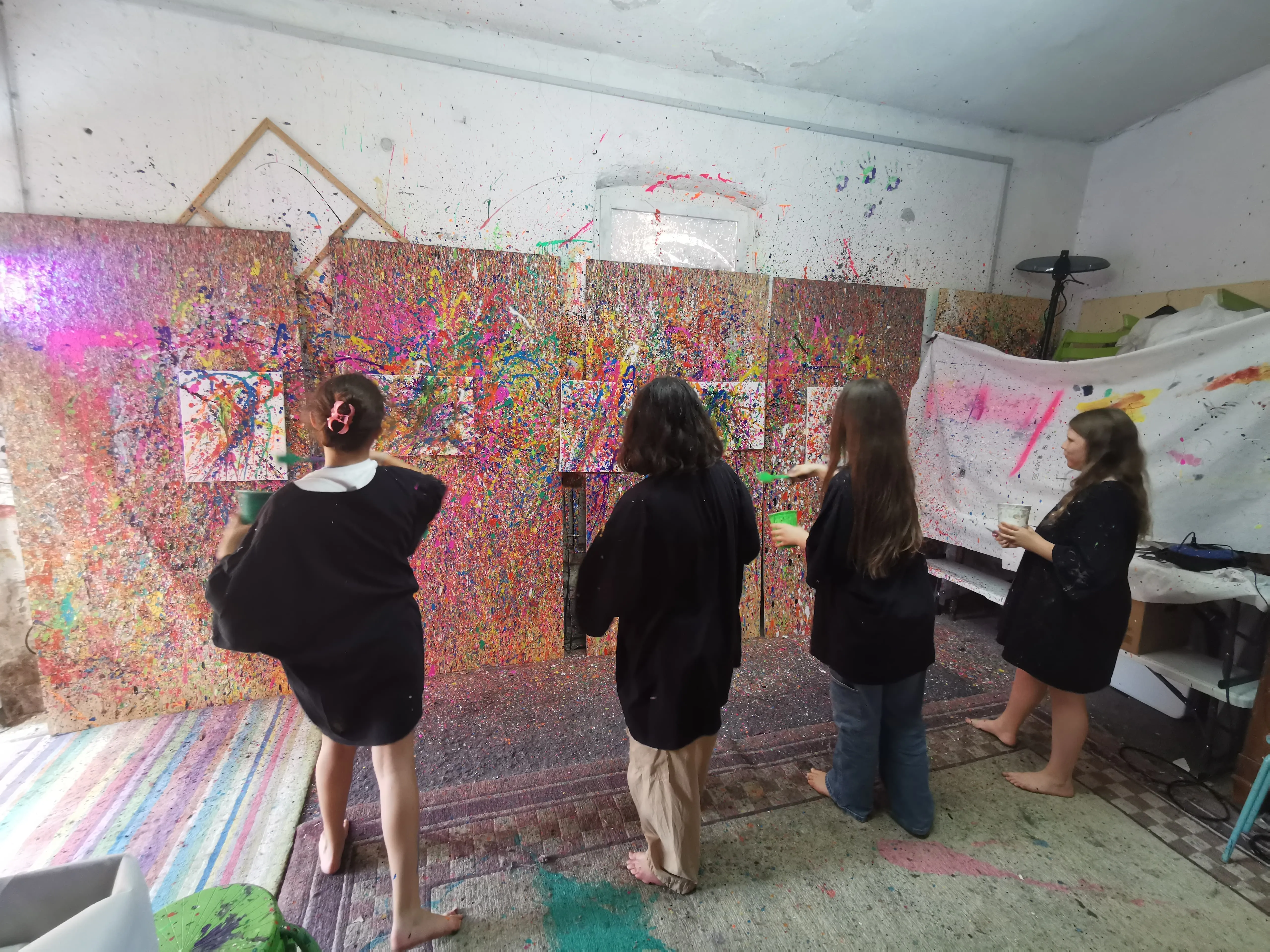 Four people painting walls with splatter technique.