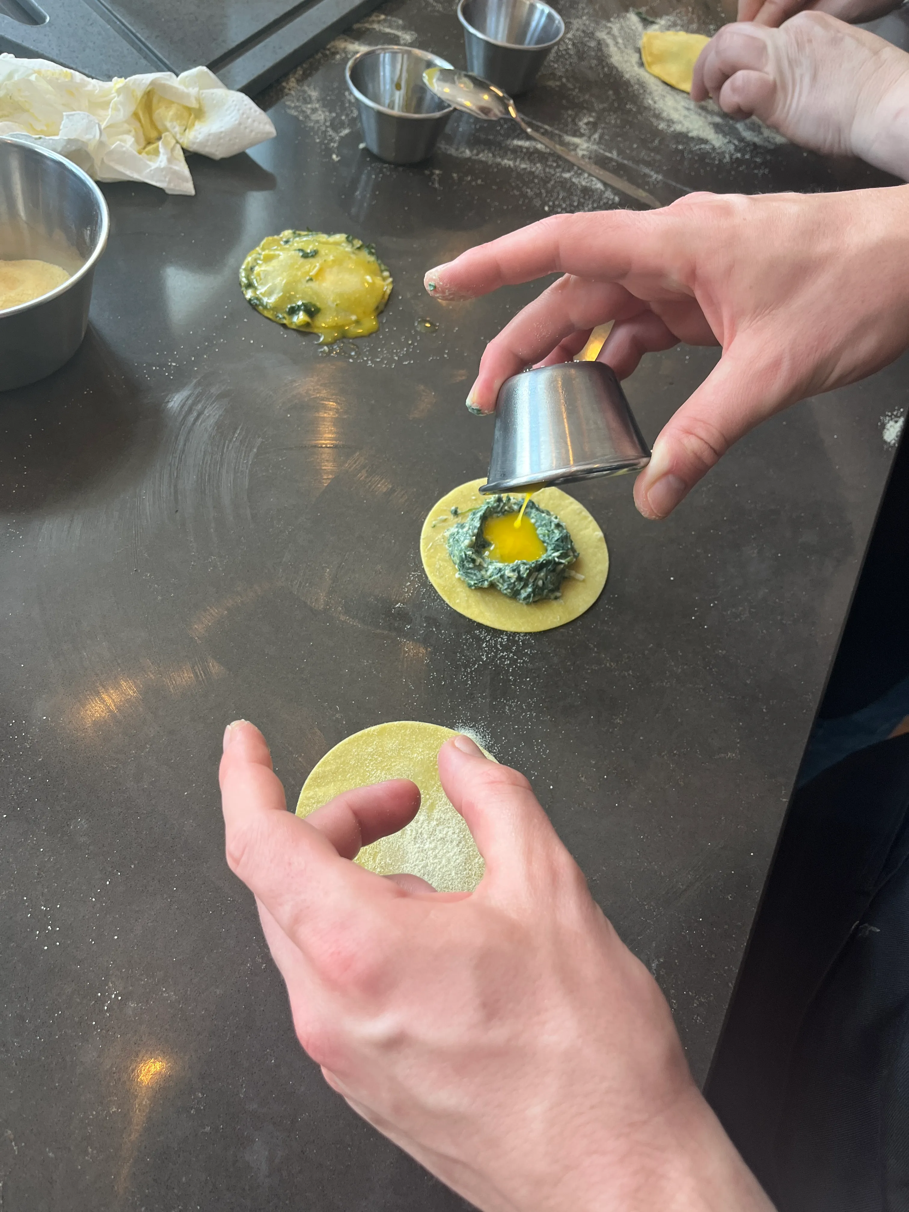 Hände bereiten Ravioli mit Spinatfüllung vor.