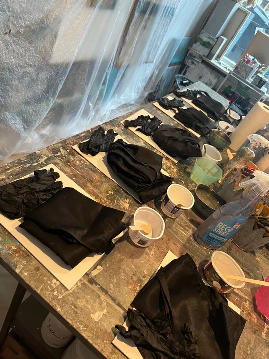 Schwarze Tücher und Handschuhe auf Werkbank.