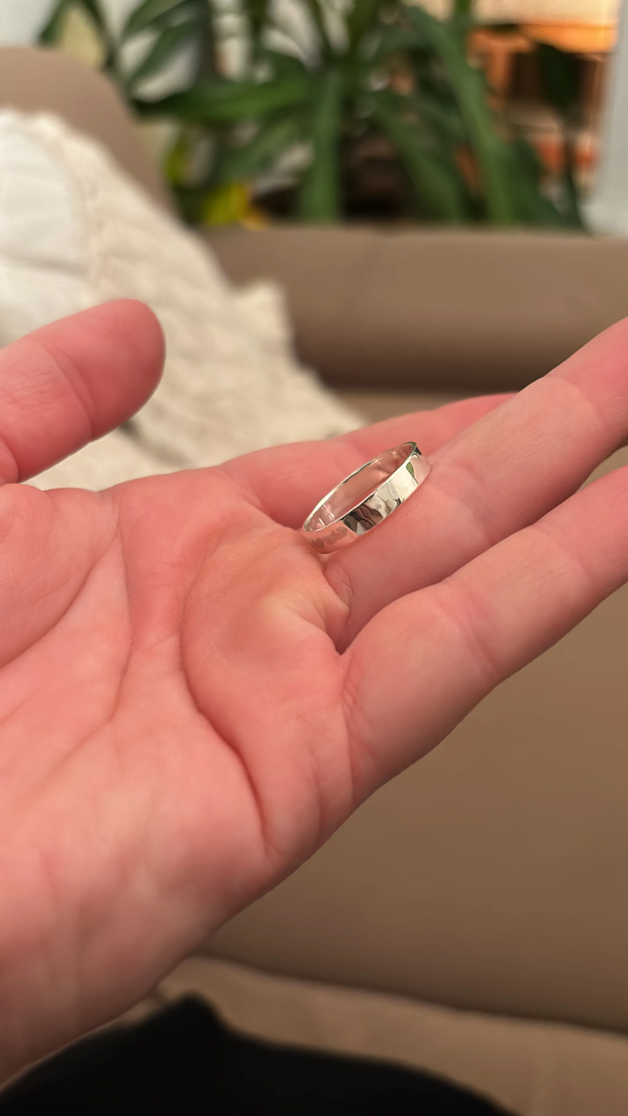 Hand hält einen Silberring in Innenraum.