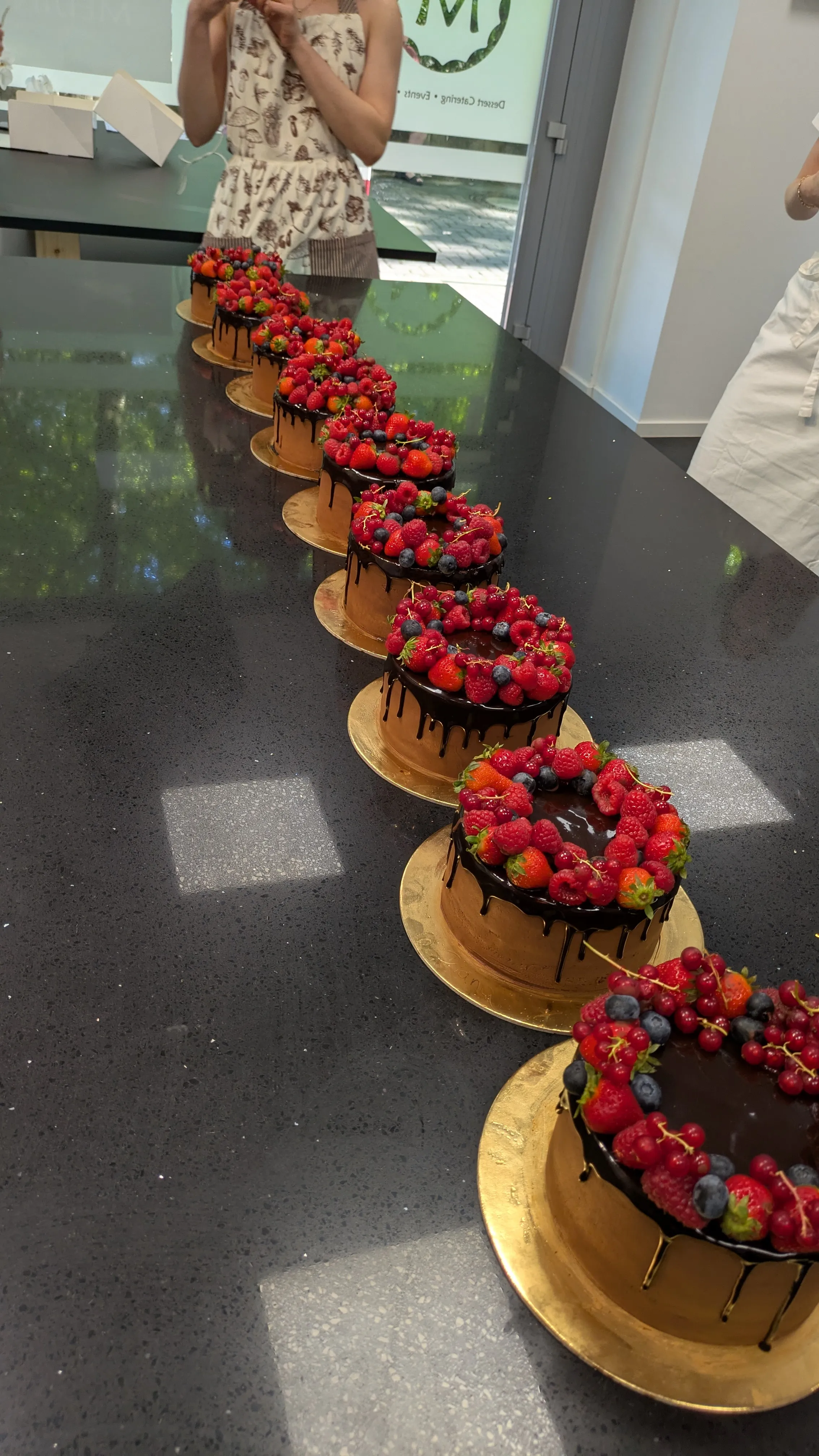 Kuchen mit Beeren auf einem reflektierenden Tisch.