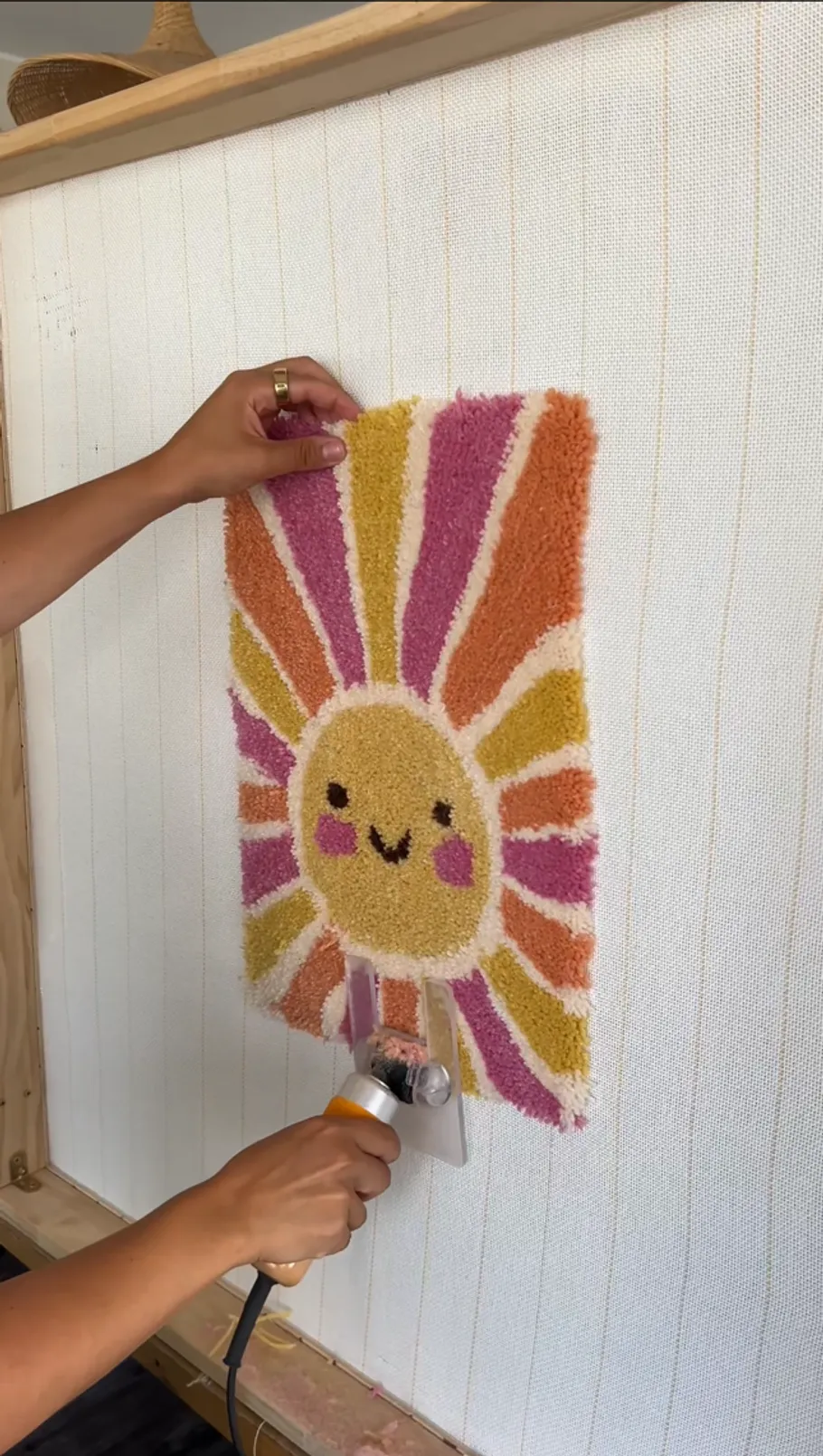 Person tuftet ein buntes lächelndes Sonnendesign.