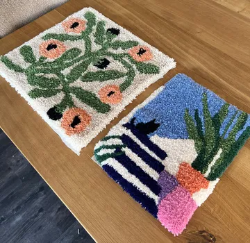 Two colorful tufted rugs on wooden table.