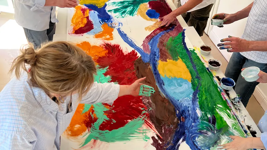 People painting on large canvas together.