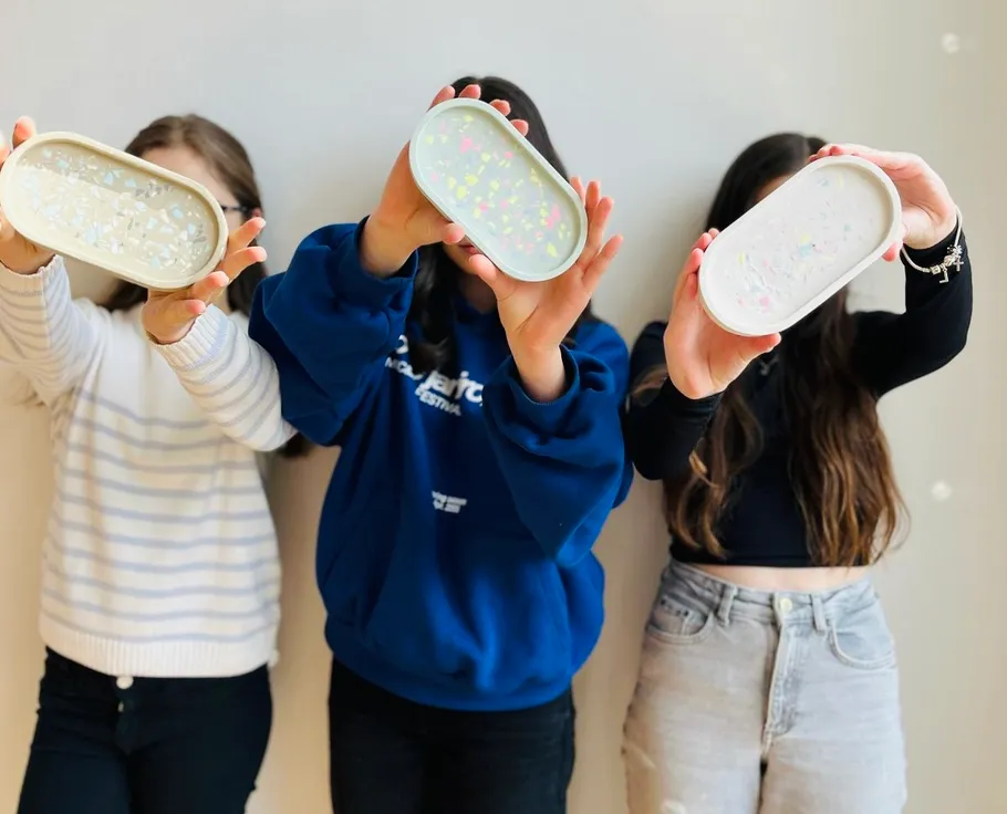Three people holding textured trays forward.