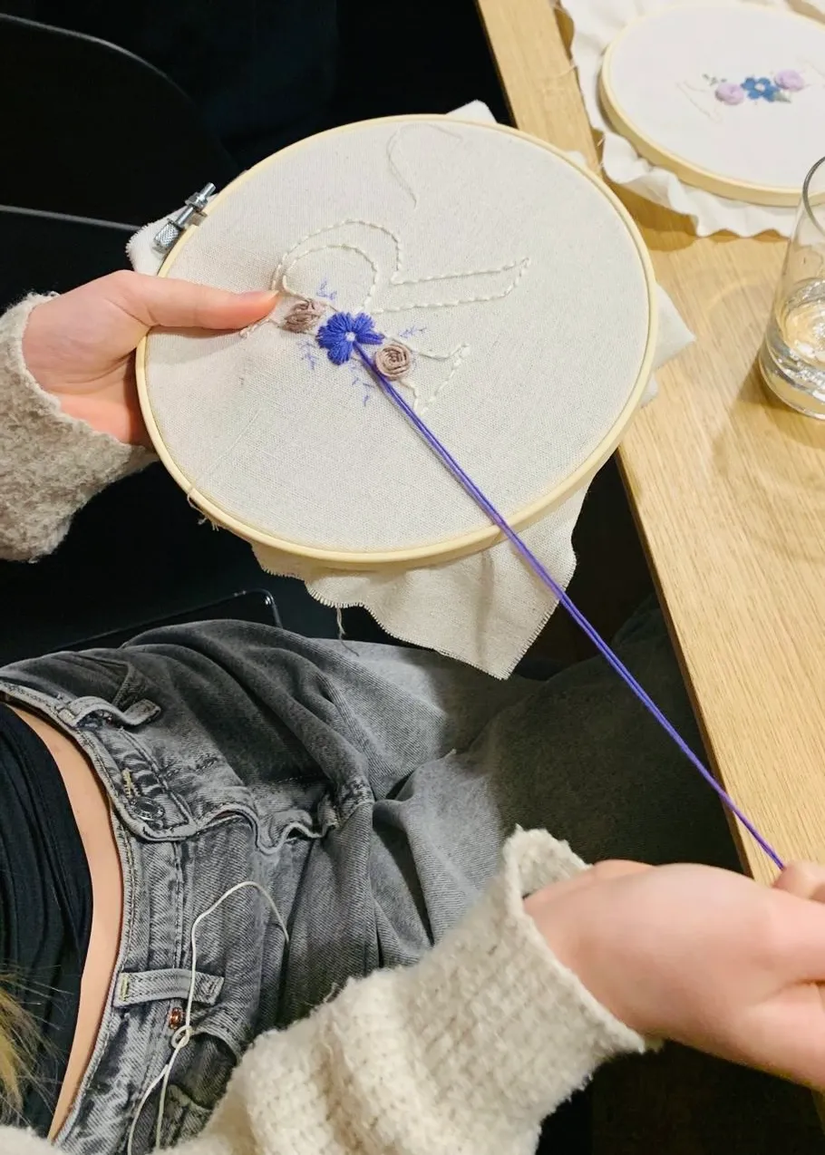 Person embroidering fabric with floral design.