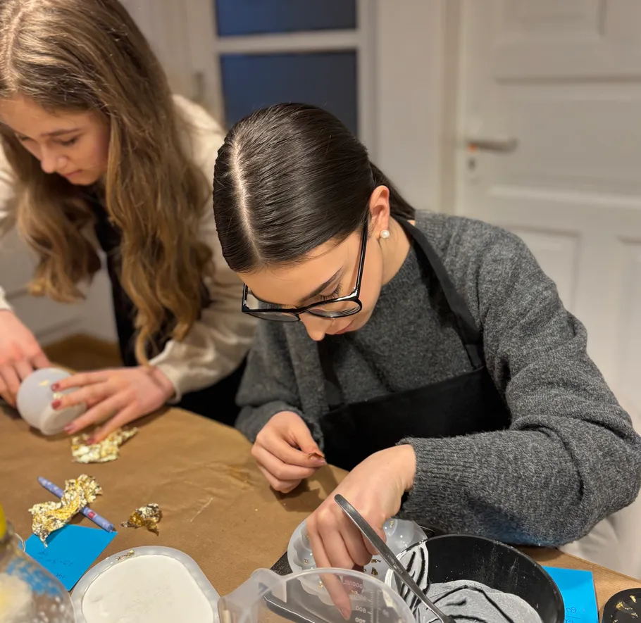 Two women crafting with gold foil indoors.