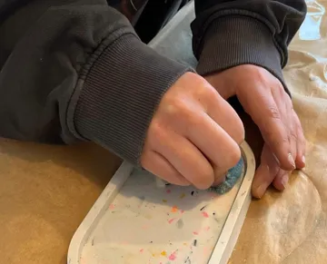 Person sanding an object on a table.