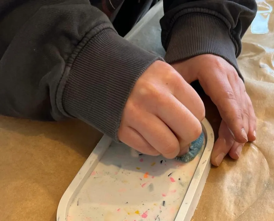 Person sanding an object on a table.
