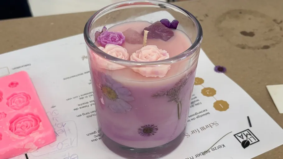 Purple candle with decorative flowers on paper.
