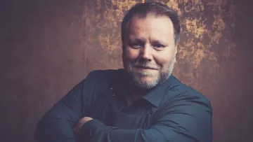 Smiling man with crossed arms indoors.