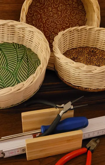 Flechtkörbe mit Werkzeugen auf Holzfläche.