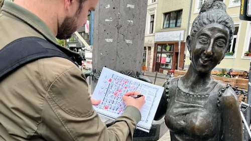 Man sketching next to a bronze statue.