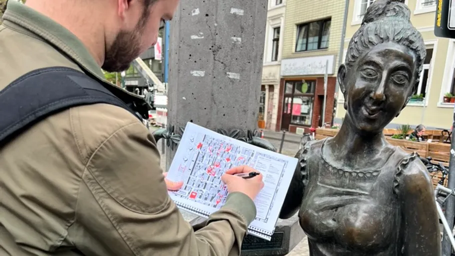 Mann skizziert neben einer Bronzestatue.