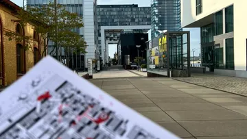 Karte in der Hand, moderne Gebäude im Hintergrund.