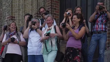 Group of people enthusiastically taking photos outside.