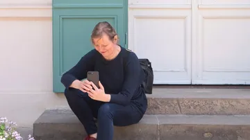 Person sitting on steps using smartphone outdoors.
