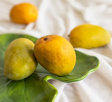 Mangoes resting on a green ceramic plate.