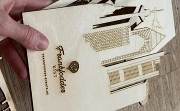 Hand holding wooden laser-cut skyline design.
