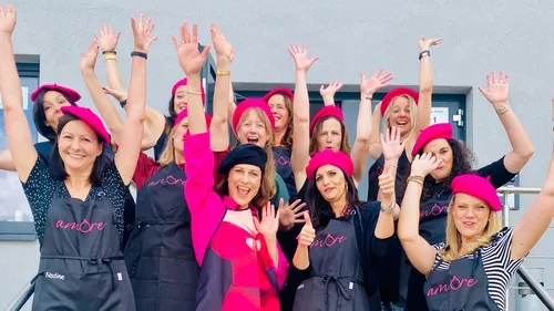 Group of women wearing berets and aprons, cheering.