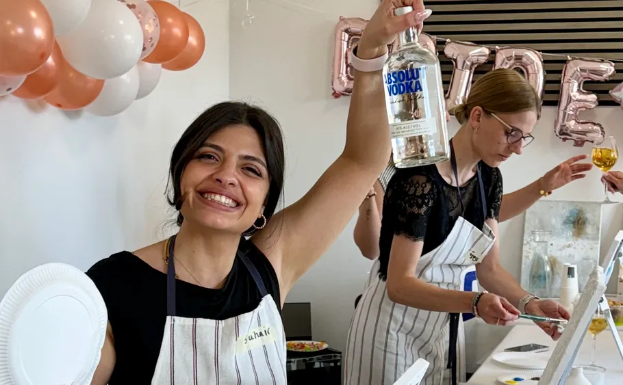 Smiling woman holds vodka bottle at party.